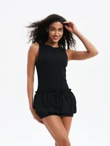 Vestido negro sin mangas, ajustado en la parte superior y con falda corta tipo globo o bombacha fruncida con cordón ajustable en la cintura.