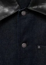 Chaqueta de denim en color azul oscuro, con diseño recto, cuello camisero, cierre frontal de botones metálicos y bolsillos de parche con solapa en el pecho.