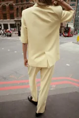 Blazer color amarillo pastel con textura, cuello solapa, manga corta con hombreras, bolsillos de vivo en delantero, forro interior y cierre frontal cruzado con botones.