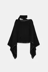 Capa negra de cuello redondo con detalle de tachas plateadas en el ruedo y pañuelo tipo bufanda integrado en el mismo tejido.