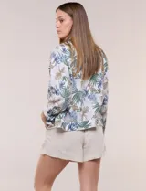 Camperita de lino liviana, marca Dash, con estampado botánico de hojas en tonos azules, verdes y tostados sobre base blanca. Presenta cierre frontal con botones, cuello clásico y bolsillos aplicados en el pecho.