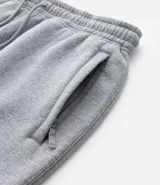 Pantalón deportivo de corte jogger, color negro, con cintura elástica ajustable mediante cordón, bolsillos laterales y puños acanalados en los tobillos. Confeccionado en tejido de algodón con interior felpudo.