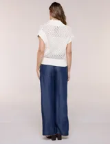 Buzo de punto color marfil, confeccionado en algodón calado con cuello alto acanalado y medio cierre metálico dorado. Presenta mangas cortas estilo japonesa con puños anchos y un zócalo acanalado en el ruedo.