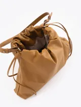 Cartera tipo shopper de cuero vacuno color tostado, con formato amplio, fruncido superior y cordones ajustables a los lados. Cuenta con tiras finas para llevar al hombro y sutil grabado de la marca en el frente.