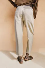 Pantalón de tiro medio color amarillo, con cintura elástica, bolsillos de plastrón en el delantero y pernera holgada que se estrecha hacia el tobillo. Cuenta con cierre frontal de cremallera y botón.