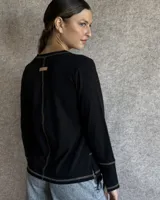 Remera blanca de manga larga con cuello en V y costuras decorativas en contraste. Incluye un lazo ajustable en el cuello con herraje metálico circular.