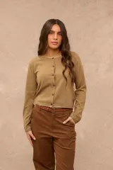 Saco tejido color taupe de manga larga, con escote redondo y cierre frontal de botones. Presenta detalles de costura en color blanco en el cuello, puños y ruedo.