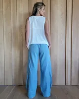 Pantalón de algodón color arena, de corte recto y holgado, con cintura elástica y detalle de costuras horizontales decorativas en la parte inferior de las piernas.