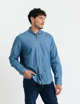 Camisa de jean de manga larga con cuello clásico, cierre frontal con botones y bolsillo tipo parche en el pecho.