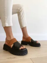 Sandalias de cuero color negro y camel, con plataforma track y hebilla ajustable.