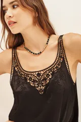 Top tipo musculosa de modal satén color crema, con detalle de encaje calado y bordados a tono en el escote delantero y en la espalda.