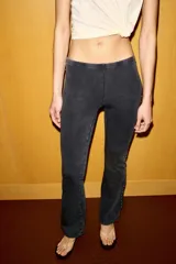 Pantalón de tiro medio con cintura elástica y corte acampanado. Presenta un acabado lavado y detalle de tachas metálicas a lo largo de las costuras laterales.
