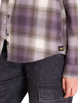 Camisa de manga larga de franela con estampado a cuadros en tonos violeta, gris y blanco, de corte relajado, con bolsillos en el pecho y cierre frontal de botones.