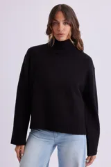 Buzo de punto en color negro, con cuello alto y puños y ruedo acanalados. Presenta un diseño de corte recto y tejido elástico.