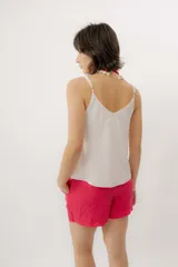 Musculosa negra con escote en V, breteles finos regulables y doble volado frontal con pespuntes.