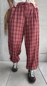 Pantalón estilo babucha color rojo con estampa a cuadros, tiro medio y cintura elástica con cordón ajustable.