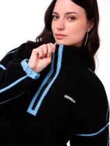 Buzo de polar negro con cierre frontal de media longitud en color celeste. Presenta detalles de ribetes celestes en las mangas y el cuello, y logo de la marca bordado en el pecho.