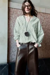 Collar de cordón fino con nudo ajustable. Presenta colgantes combinados que incluyen una pieza metálica, una piedra decorativa y un pequeño monedero circular de piel con cierre.