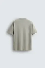 Camiseta de corte relajado (relaxed fit) color blanco roto o crema, con cuello redondo y manga corta.