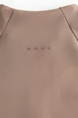 Campera deportiva de corte ajustado, color marrón tostado, con cuello elevado, cierre frontal completo, mangas raglán con abertura para el pulgar y bolsillos laterales con cierre.