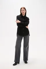 Camisa de jean negro con diseño de frunces verticales en el frente, cuello clásico, cierre frontal con botones y mangas largas con puños abotonados.