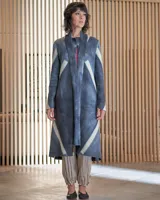 Tapado largo de lana merino afieltrada, color fucsia con diseño tie-dye artesanal en tonos claros y crudos. Tiene cuello que se prolonga a modo de cinto, aberturas laterales y bolsillos.