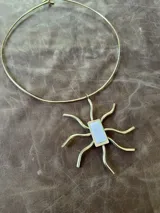 Gargantilla dorada con dije en bronce y nácar.