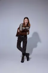 Pantalón de corte recto y tiro medio, confeccionado en tejido con patrón de cuadros oscuros. Presenta bolsillos frontales amplios y terminación con dobladillo en los tobillos.