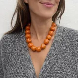 Collar de diseño artesanal compuesto por múltiples hileras de cuentas de resina pulida en una paleta de colores vibrantes que incluye tonos marrones, grises, verdes, naranjas y bordó.