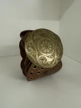 Cinto faja de cuero sintético negro con hebilla metálica dorada con diseño circular calado.