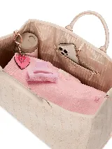 Bolso tote de mano color beige con monograma estampado, asas superiores y correa cruzada desmontable. Cuenta con cierre superior de cremallera y herrajes dorados.