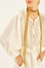 Camisa corta de corte regular, confeccionada en algodón con hilos de lurex. Mangas amplias con elástico interno.