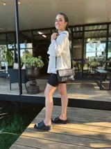 Cartera bandolera de cuero negro con textura tipo cocodrilo, correa larga regulable y forro interno de tela.