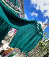 Sweater tejido a mano de lana merino color verde oscuro, con cuello alto, mangas abullonadas y detalle de bordado floral artesanal en el canesú.