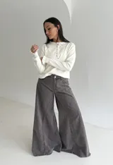 Sweater de punto color marrón chocolate, con cuello redondo y cierre frontal parcial con botones. Presenta mangas largas con puños acampanados y detalle de volados.