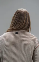 Sweater de punto con diseño de rayas verticales en tonos beige y marrón, cuello redondo y corte oversize.