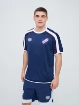Remera deportiva de entrenamiento Umbro del Club Nacional de Football, color azul marino con detalles en blanco y líneas rojas en los hombros. Cuenta con el logo de la marca y el escudo del club en el pecho.