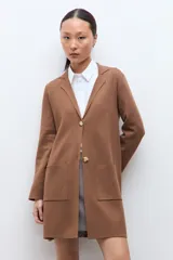 Sacón azul marino de corte largo, con cuello solapa, cierre frontal de dos botones dorados y bolsillos de parche.