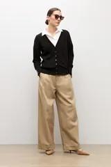 Cardigan negro con escote en V, manga larga y cierre frontal con botones pequeños. Presenta puños acanalados con detalle de botones decorativos.