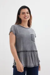 Remera gris con cuello redondo, mangas cortas y corte peplum con volados en la parte inferior. Tiene un bolsillo pequeño en el pecho.
