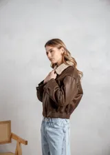 Campera de ecocuero color marrón, con forro interno de corderito sintético, cuello clásico, cierre frontal y bolsillos laterales.