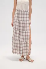 Falda larga de algodón con diseño a cuadros en tonos beige, blanco, marrón y celeste. Presenta un diseño escalonado con volados y una abertura lateral pronunciada.