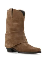 Bota de caña media confeccionada en gamuza color marrón, con diseño de pliegues naturales y caída suave. Presenta punta afinada y taco acuñado, con un estilo inspirado en la estética western.
