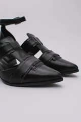 Sandalias plateadas con punta cerrada, tiras entrecruzadas y pulsera al tobillo con hebilla. Taco cuadrado negro.