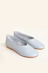 Chatitas de cuero color celeste, con borde superior fruncido y detalle trenzado. Suela plana de cuero con taco bajo.