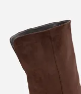 Bota over the knee color marrón, con acabado efecto gamuza y caída fruncida a lo largo de la caña. Presenta punta fina y tacón bajo y fino de 5 cm.