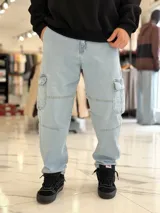 Pantalón cargo de jean azul con múltiples bolsillos en los laterales y diseño holgado.