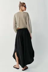 Pantalón fluido de tiro alto en color blanco, con pinzas delanteras, cintura elástica en la espalda y perneras anchas con aberturas laterales pronunciadas.