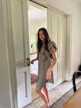 Vestido corto color verde oliva de lino con cuello mao fruncido, volados en los hombros, caída recta y botones al frente.