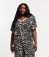 Blusa de crepé con estampa de manchas en blanco y negro, mangas cortas y escote en pico con borde contrastante.